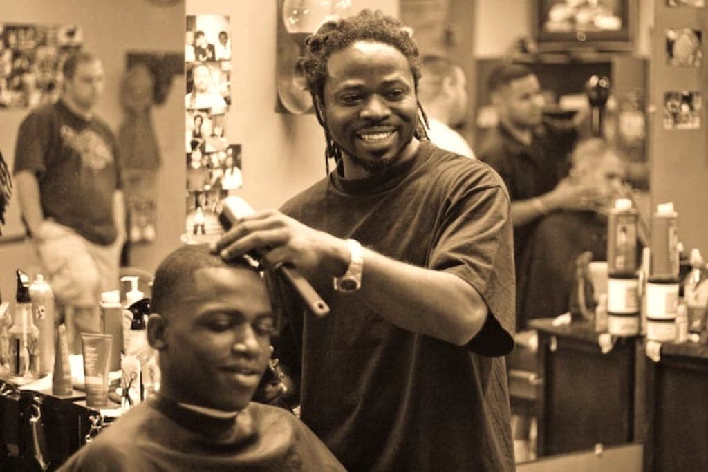 Barbier souriant qui passe la tondeuse sur la nuque d'un jeune client